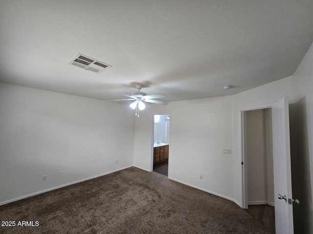 unfurnished bedroom featuring dark colored carpet, ceiling fan, and ensuite bath