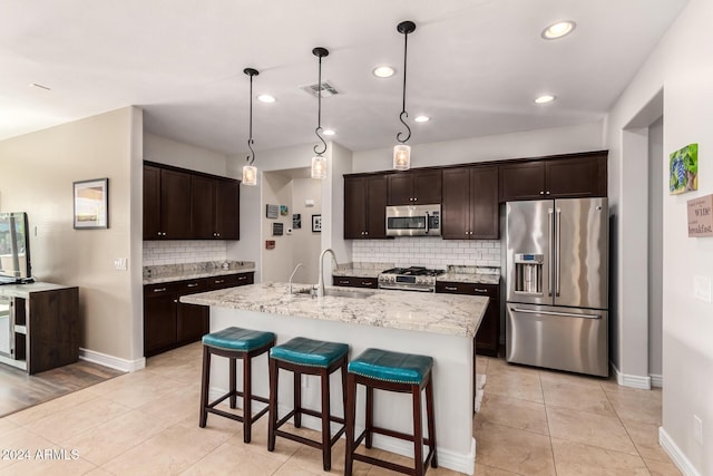 kitchen featuring decorative light fixtures, an island with sink, premium appliances, a kitchen bar, and dark brown cabinets