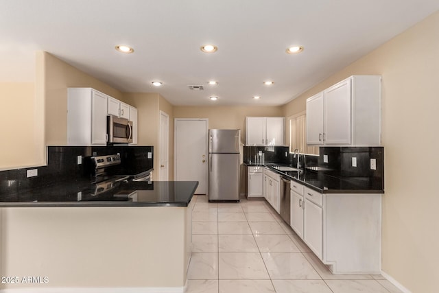 kitchen with white cabinets, stainless steel appliances, kitchen peninsula, and sink