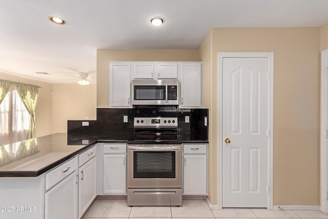 kitchen with kitchen peninsula, ceiling fan, white cabinets, tasteful backsplash, and stainless steel appliances