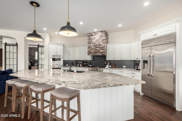 12834 W Forest Pleasant Pl, Peoria, AZ 85383 - kitchen featuring stainless steel appliances, a sink, a barn door, tasteful backsplash, and white cabinets