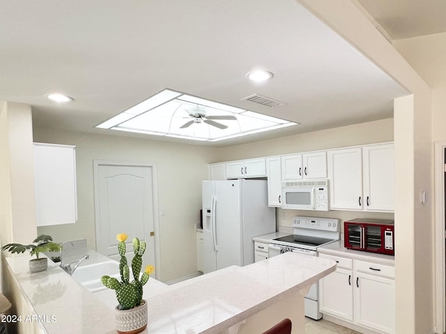 kitchen with ceiling fan, kitchen peninsula, white appliances, a skylight, and white cabinets