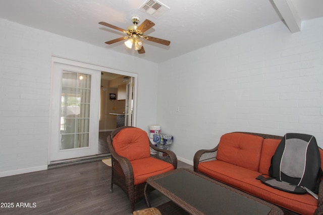 sitting room featuring visible vents, ceiling fan, brick wall, and wood finished floors