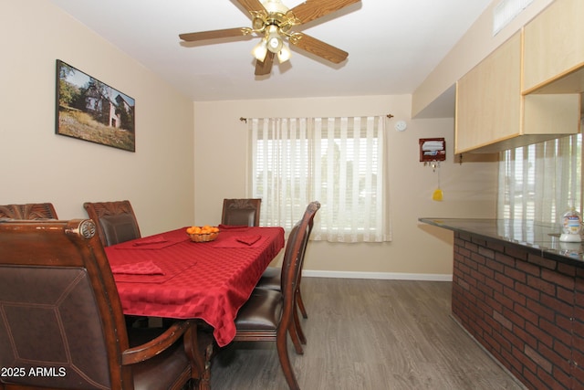 dining area with a ceiling fan, baseboards, and wood finished floors