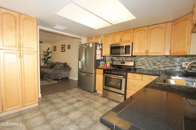 kitchen with tasteful backsplash, light brown cabinets, appliances with stainless steel finishes, and a sink