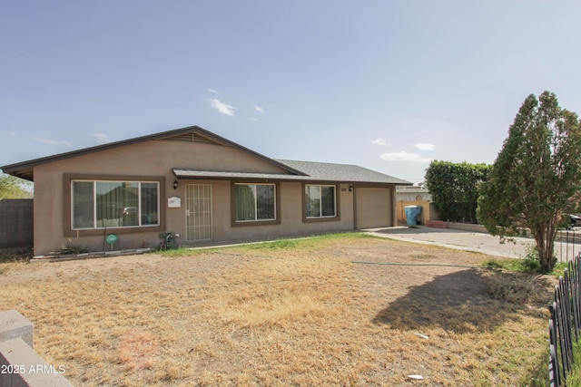 view of front of home featuring a garage, concrete driveway, fence, and stucco siding