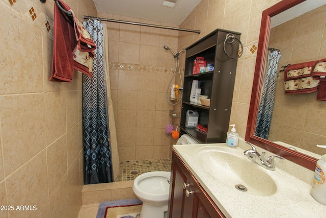 bathroom with toilet, a stall shower, vanity, and tile walls