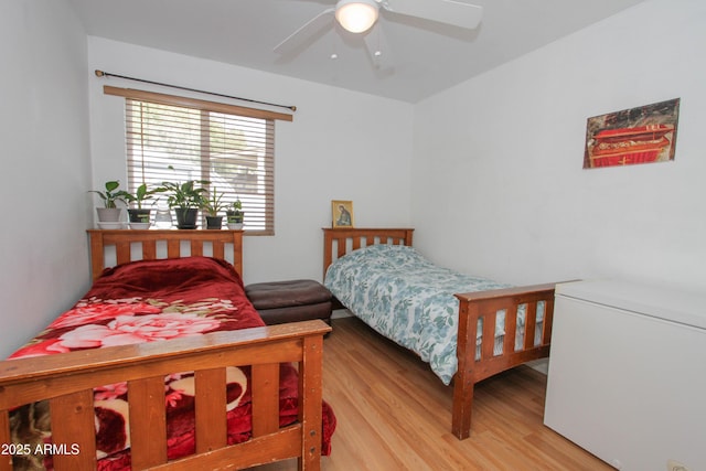 bedroom with a ceiling fan, light wood-style flooring, and white fridge