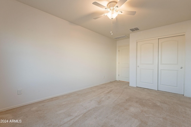 unfurnished bedroom with light carpet, a closet, and ceiling fan