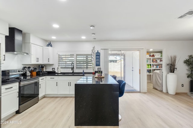 kitchen featuring white cabinets, wall chimney range hood, sink, light hardwood / wood-style flooring, and electric range