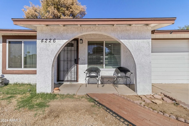 view of exterior entry featuring a garage and a patio