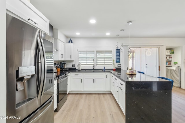 kitchen featuring pendant lighting, sink, appliances with stainless steel finishes, light hardwood / wood-style floors, and white cabinetry