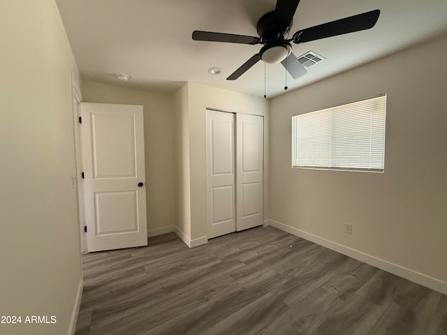 unfurnished bedroom featuring ceiling fan, a closet, and dark wood-type flooring