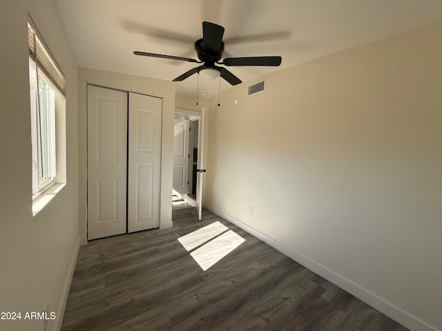 unfurnished bedroom featuring a closet, ceiling fan, and dark wood-type flooring