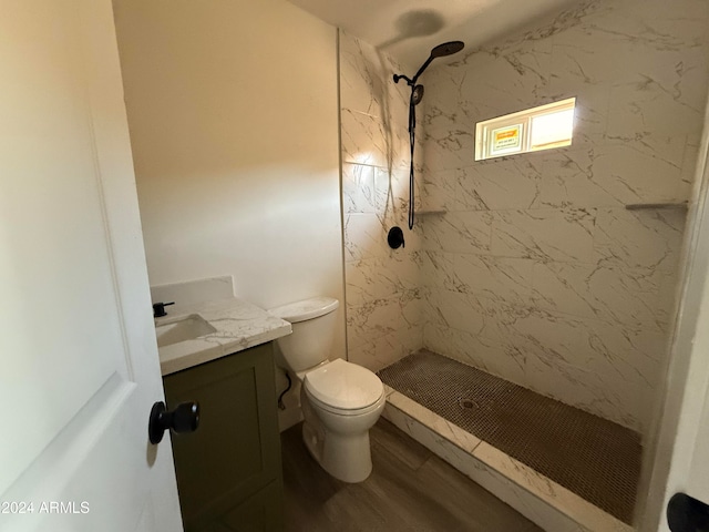 bathroom with a tile shower, toilet, vanity, and hardwood / wood-style flooring