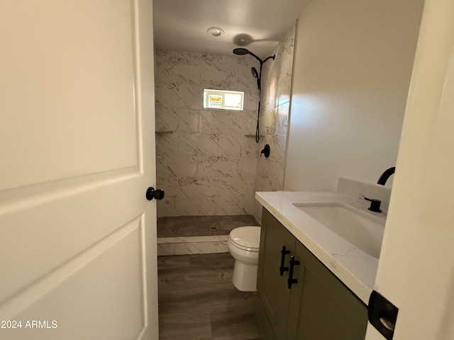 bathroom featuring tiled shower, vanity, hardwood / wood-style flooring, and toilet