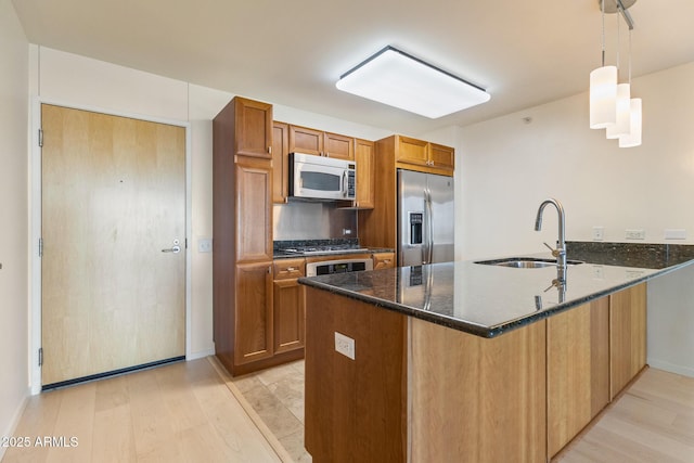 4808 N 24th St Unit 923, Phoenix, AZ 85016 - kitchen featuring appliances with stainless steel finishes, a peninsula, light wood-type flooring, and brown cabinets