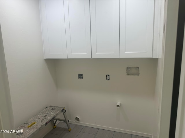 washroom with hookup for an electric dryer, hookup for a washing machine, light hardwood / wood-style floors, and cabinets