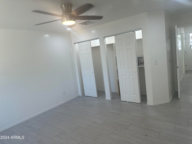 unfurnished bedroom with two closets and ceiling fan