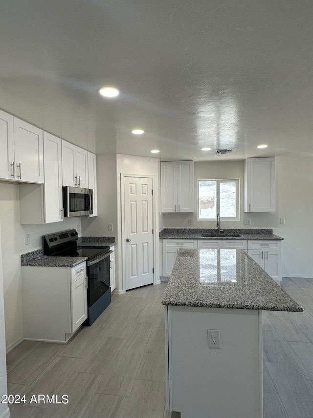 kitchen featuring white cabinetry, black electric range oven, and light hardwood / wood-style floors