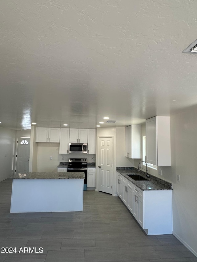 kitchen with dark stone counters, sink, white cabinets, and stainless steel appliances