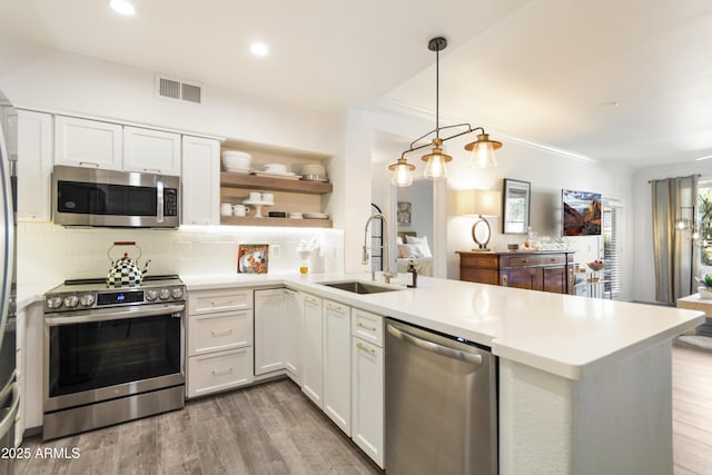 kitchen with sink, white cabinetry, kitchen peninsula, pendant lighting, and stainless steel appliances