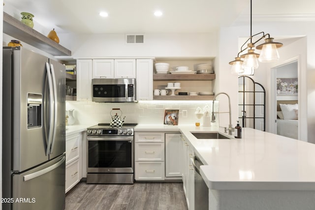 kitchen featuring sink, appliances with stainless steel finishes, pendant lighting, decorative backsplash, and white cabinets