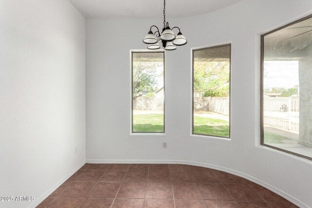spare room featuring baseboards, an inviting chandelier, and dark tile patterned flooring