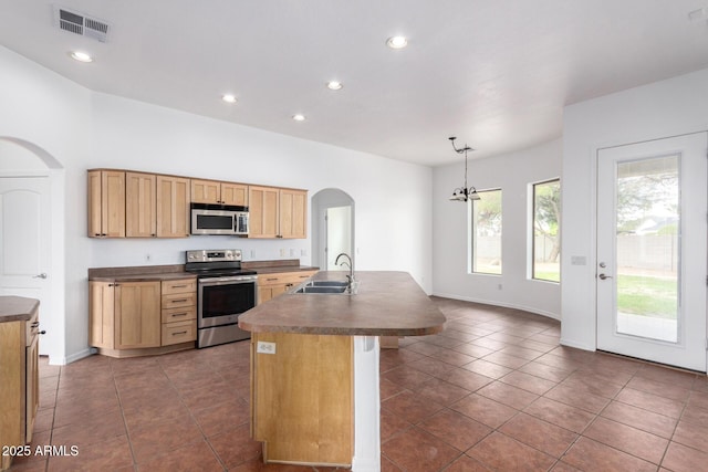 kitchen featuring visible vents, arched walkways, a sink, appliances with stainless steel finishes, and dark countertops