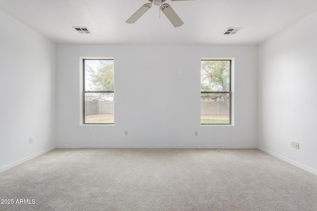 unfurnished room with visible vents, light colored carpet, and a healthy amount of sunlight