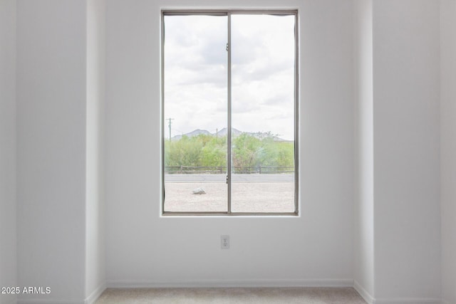 spare room featuring light carpet and baseboards
