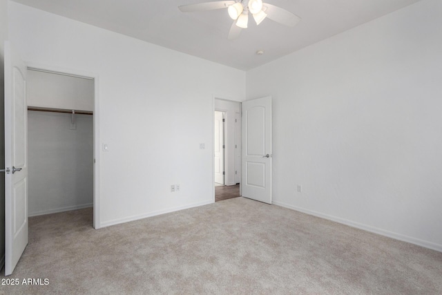 unfurnished bedroom featuring baseboards, a closet, a spacious closet, carpet flooring, and ceiling fan