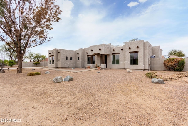 back of house featuring stucco siding and fence