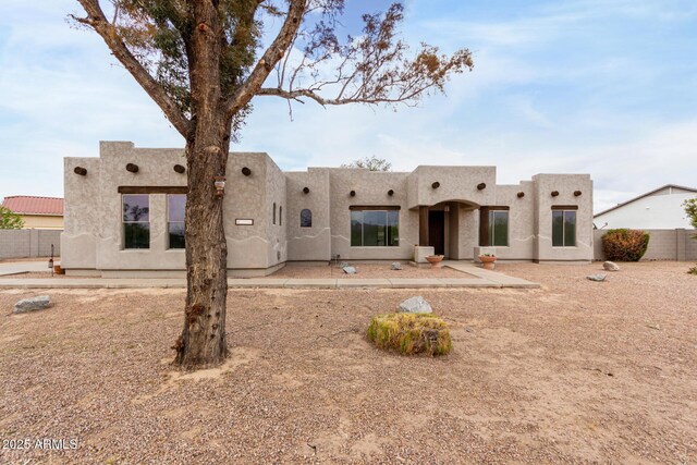 rear view of house featuring stucco siding and fence