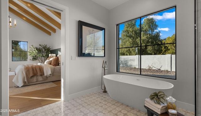 bathroom with a notable chandelier, vaulted ceiling, and a bathing tub