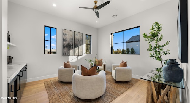 sitting room with a healthy amount of sunlight, ceiling fan, and light hardwood / wood-style flooring