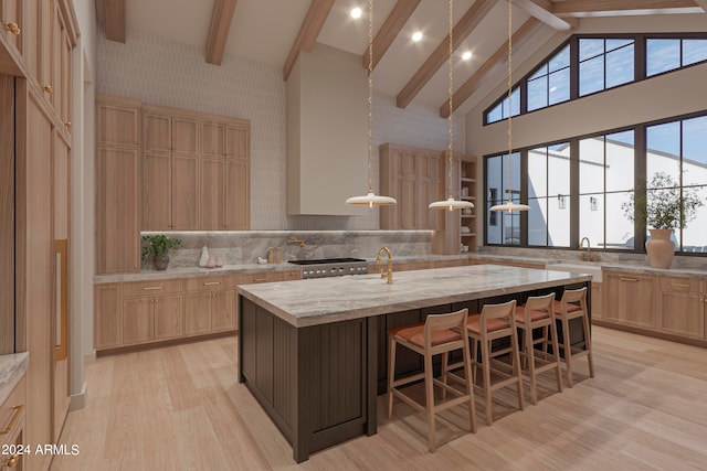 kitchen with pendant lighting, light hardwood / wood-style flooring, a kitchen island with sink, light stone counters, and light brown cabinets