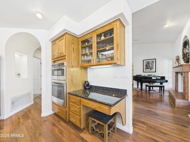 2015 W Shadow Valley Ranch Rd, Prescott, AZ 86305 - kitchen with dark stone counters, glass insert cabinets, dark wood finished floors, double oven, and arched walkways