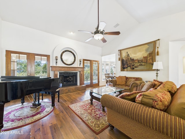 living room featuring wood-type flooring, lofted ceiling, a ceiling fan, a fireplace, and french doors