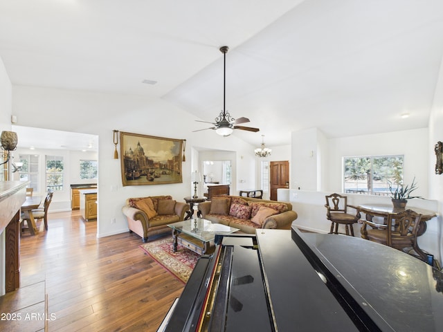 living area featuring a chandelier, hardwood / wood-style floors, lofted ceiling, ceiling fan, and baseboards