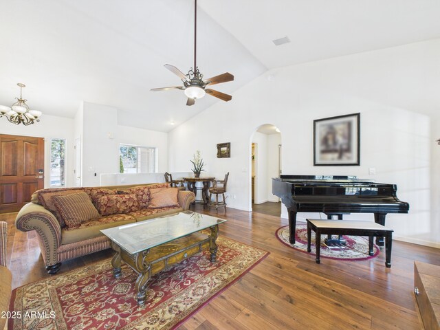 living area featuring arched walkways, a ceiling fan, a chandelier, wood finished floors, and high vaulted ceiling