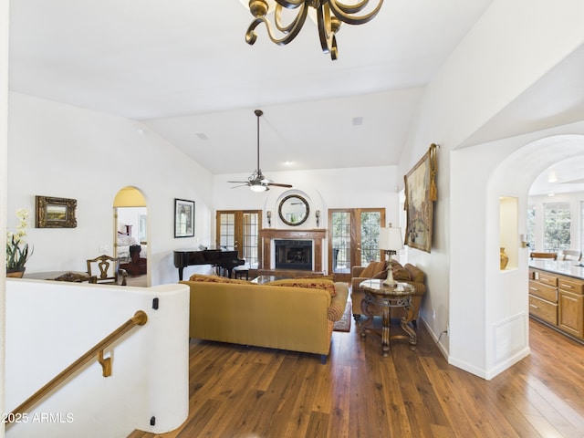 living room featuring arched walkways, vaulted ceiling, dark wood-style floors, and a chandelier