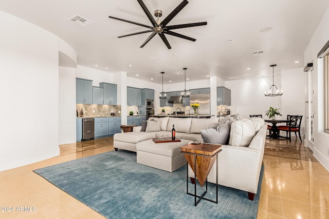 living room featuring sink, light tile patterned flooring, and ceiling fan with notable chandelier