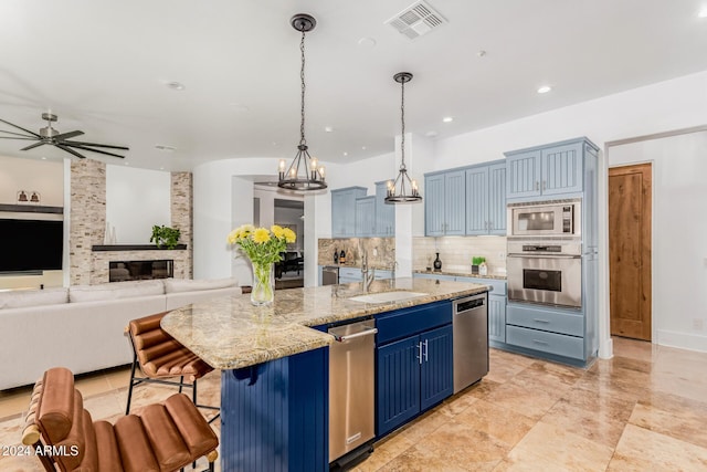 kitchen featuring blue cabinetry, a large island, hanging light fixtures, stainless steel appliances, and a breakfast bar area