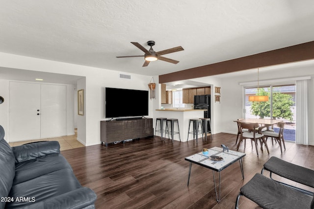 living room with a textured ceiling, ceiling fan, and hardwood / wood-style floors