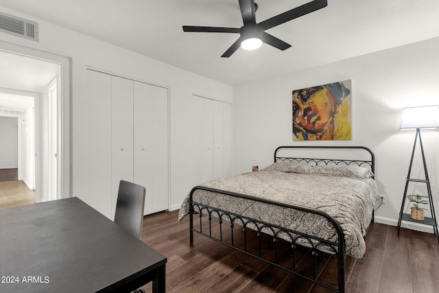 bedroom featuring multiple closets, dark wood-type flooring, and ceiling fan