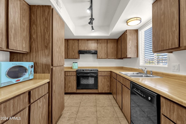 kitchen featuring track lighting, light tile patterned floors, black appliances, sink, and a tray ceiling