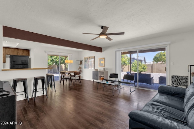 living room featuring a textured ceiling, ceiling fan, and dark hardwood / wood-style flooring