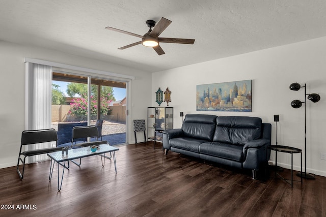 living room featuring dark hardwood / wood-style flooring, ceiling fan, and a textured ceiling