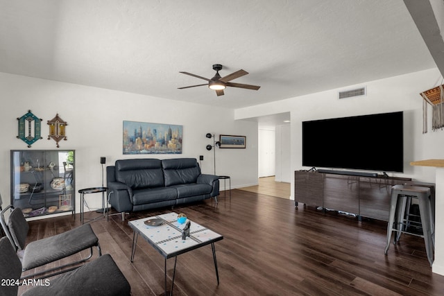 living room featuring dark hardwood / wood-style flooring, ceiling fan, and a textured ceiling